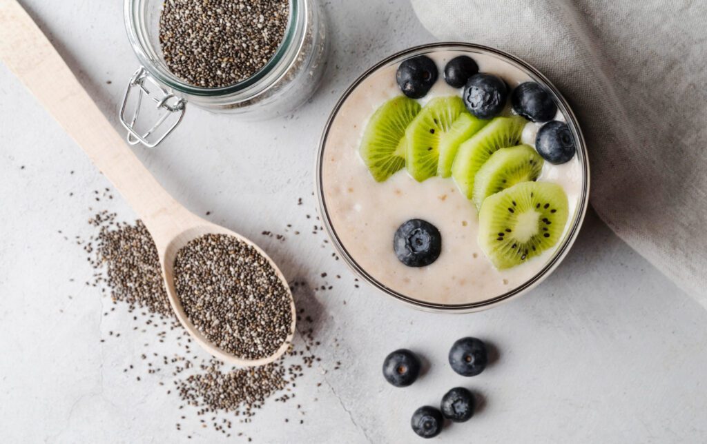 A wooden spoon scooping black and white chia seeds from a ceramic bowl